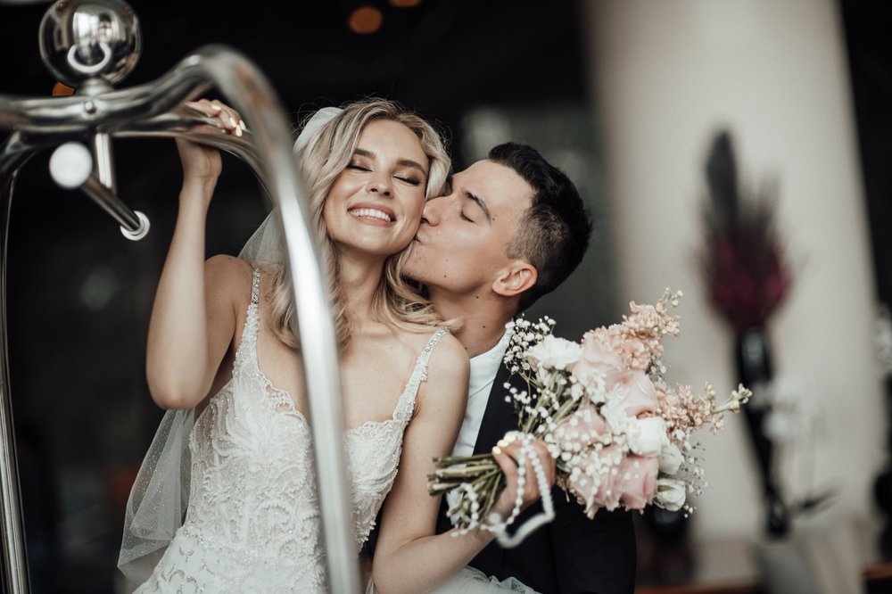 Bride smiling as the groom kisses her cheek