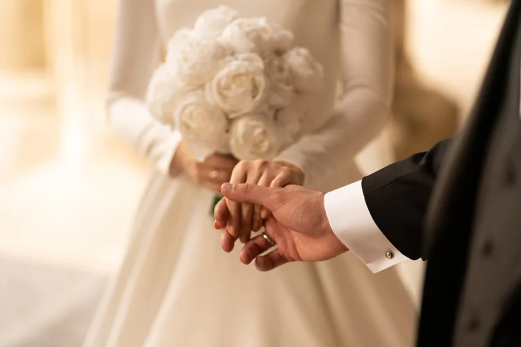 Bride and groom holding hands with a white bouquet