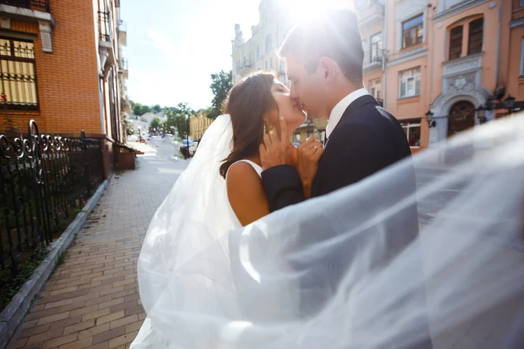 Couple kissing as the veil blows in the sun