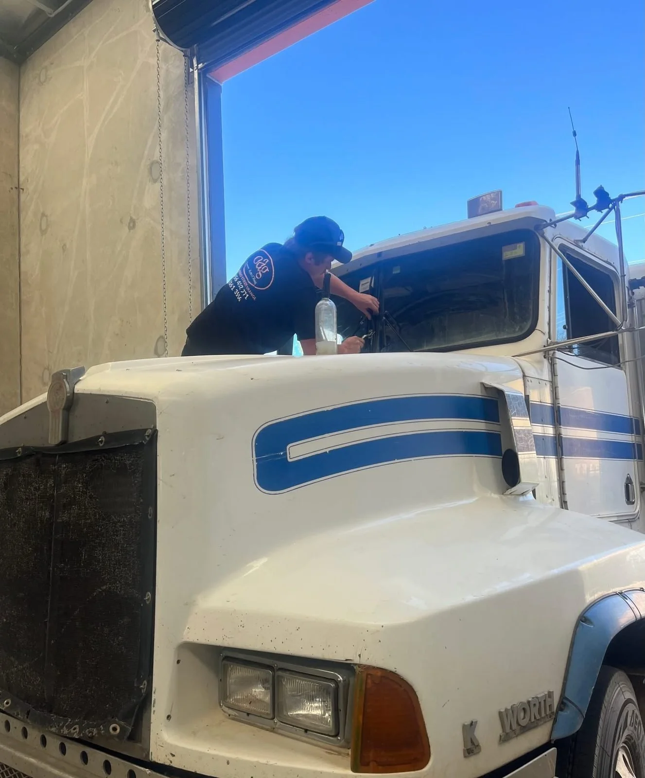 Orange Auto Glass technician fitting a windscreen to an International truck onsite