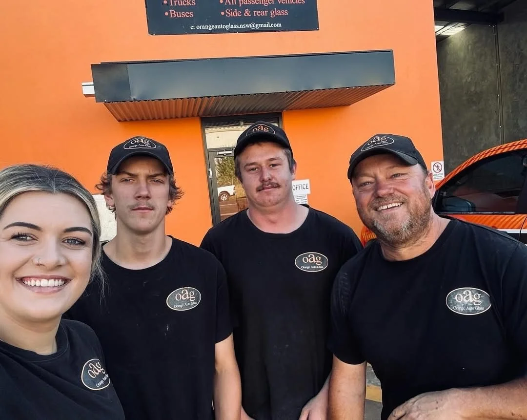 The Orange Auto Glass team in black oag uniforms outside the orange workshop office