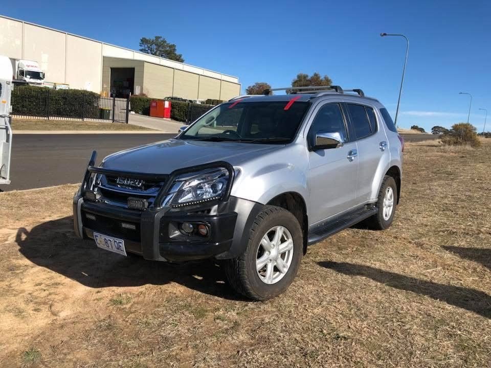 Silver Isuzu MU-X 4WD with a freshly fitted windscreen, taped while the adhesive cures