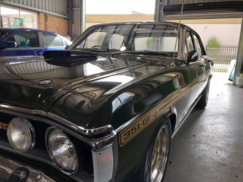 Front of a classic black car in the Orange Auto Glass workshop