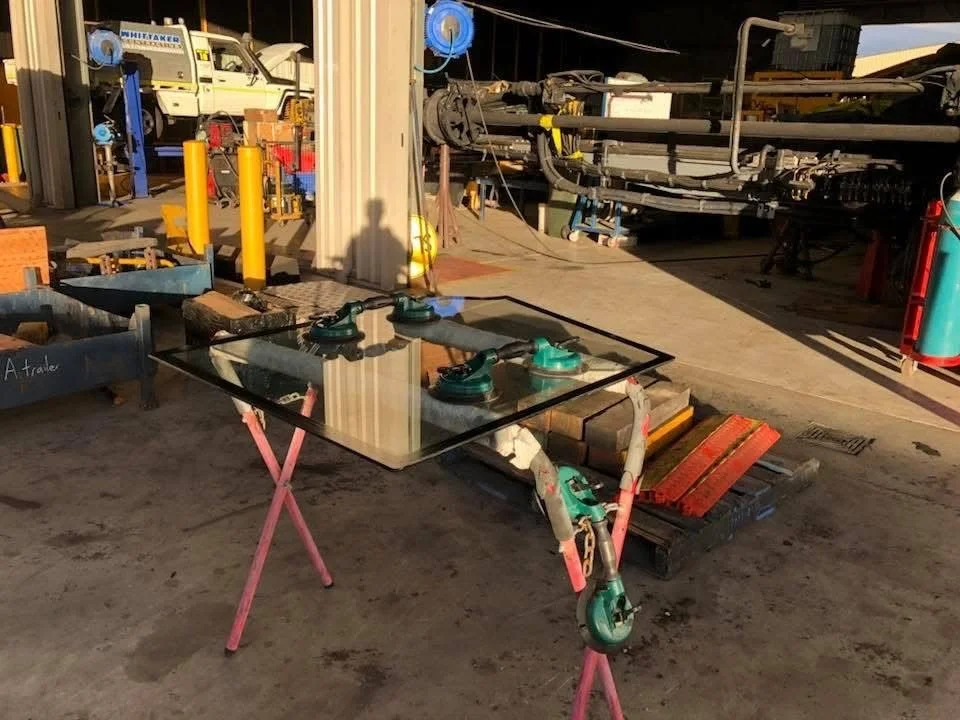 Flat laminated glass panel on a stand with suction cups, cut to size for a machinery cab