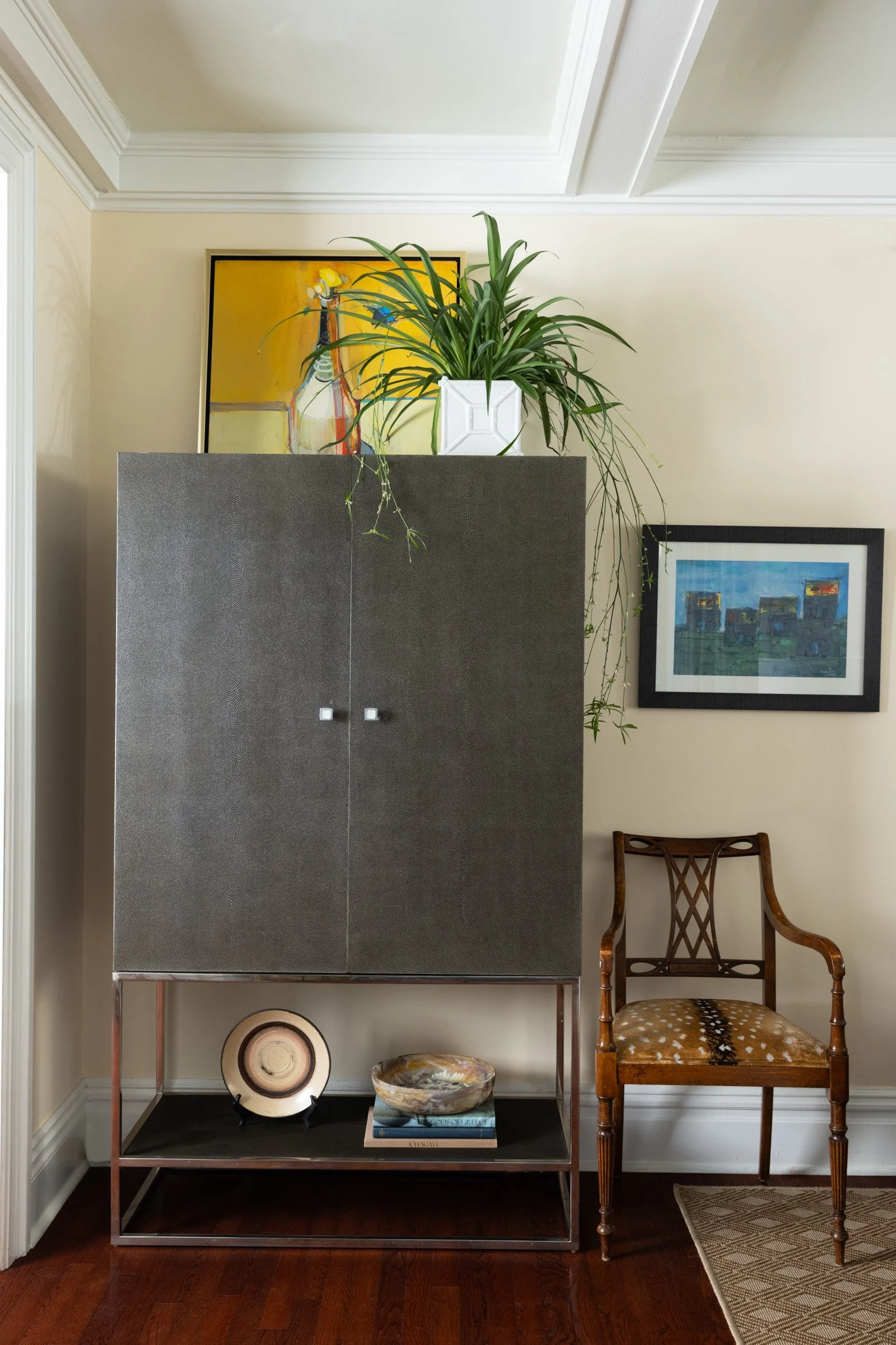 Gray cabinet with a potted plant, framed art and an antique side chair