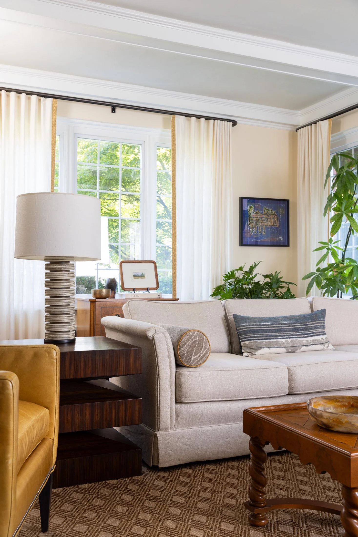 Cream sofa and gold velvet chair beside full-length curtains in a bright living room