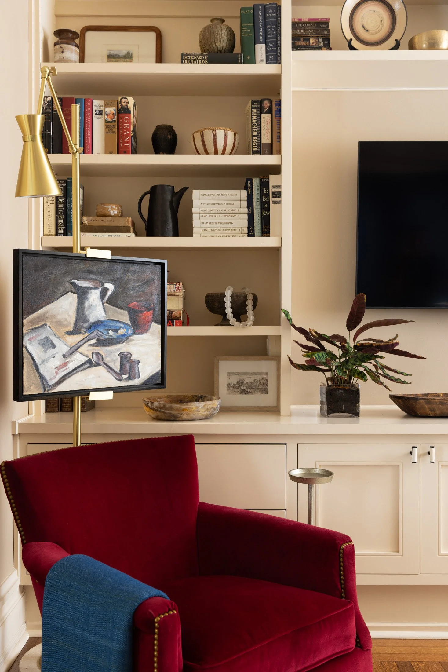 Red armchair beside bookshelves filled with art, books and collected objects