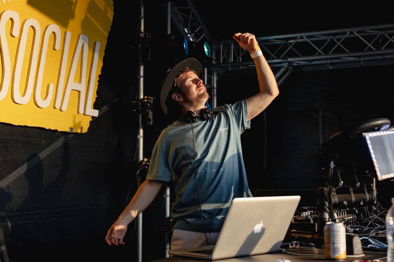A DJ lifting a hand above the decks at the Summer Social Main Stage