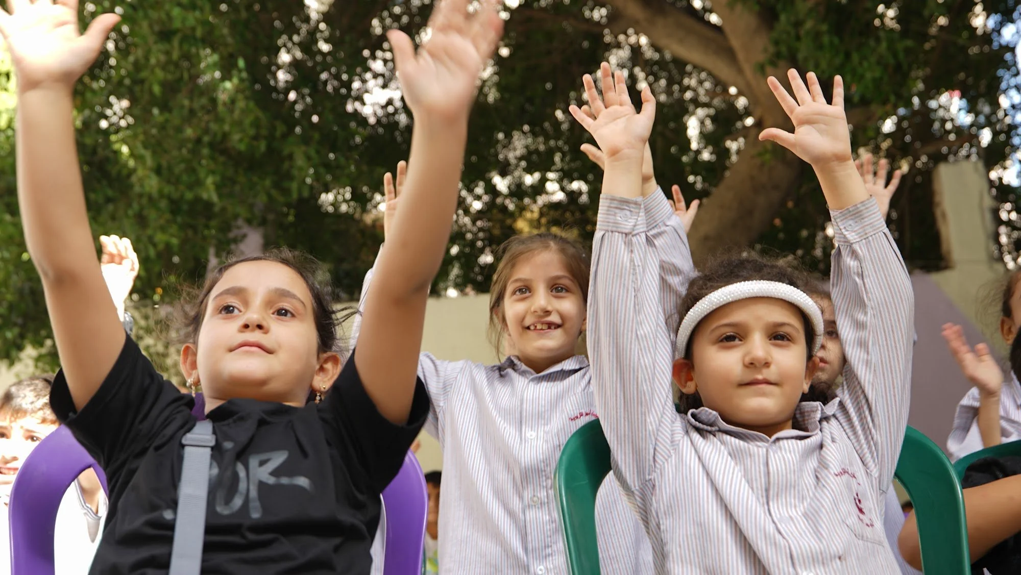 Children cheering with their arms in the air during a Make A Kid Happy school visit