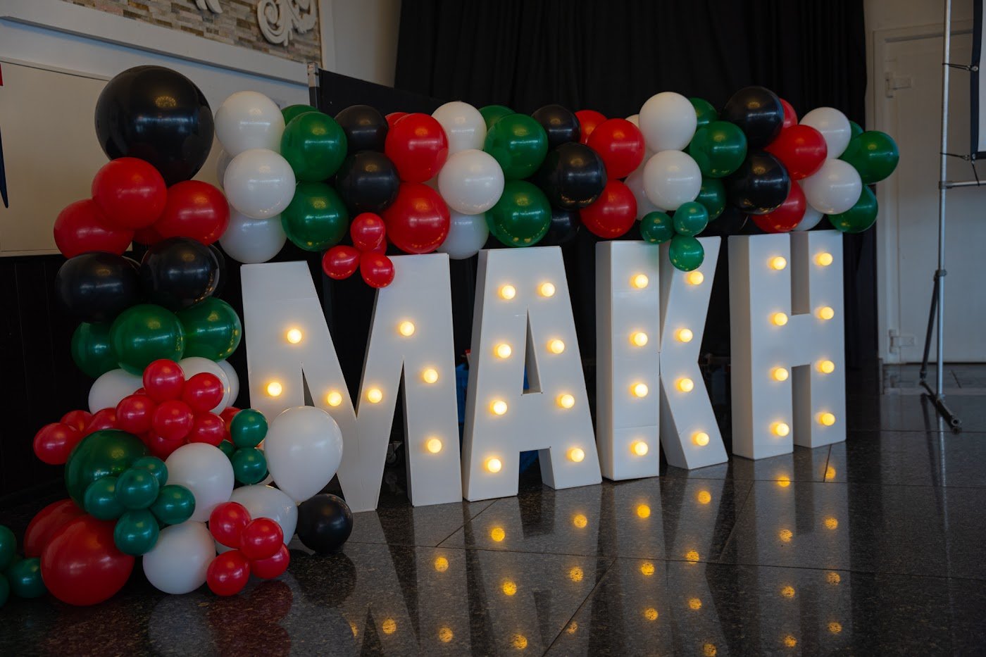 Light-up MAKH letters and balloons at a Make A Kid Happy benefit evening