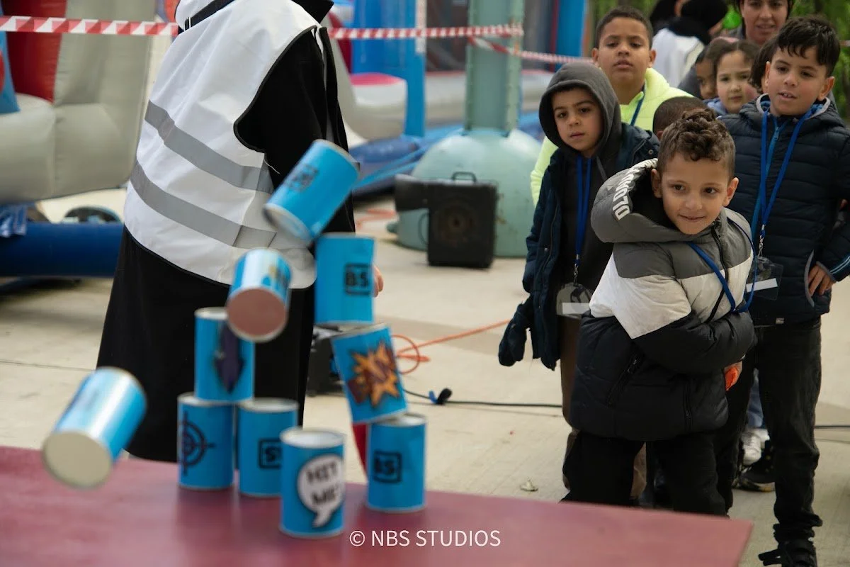 Kids lining up to knock over a pyramid of cans