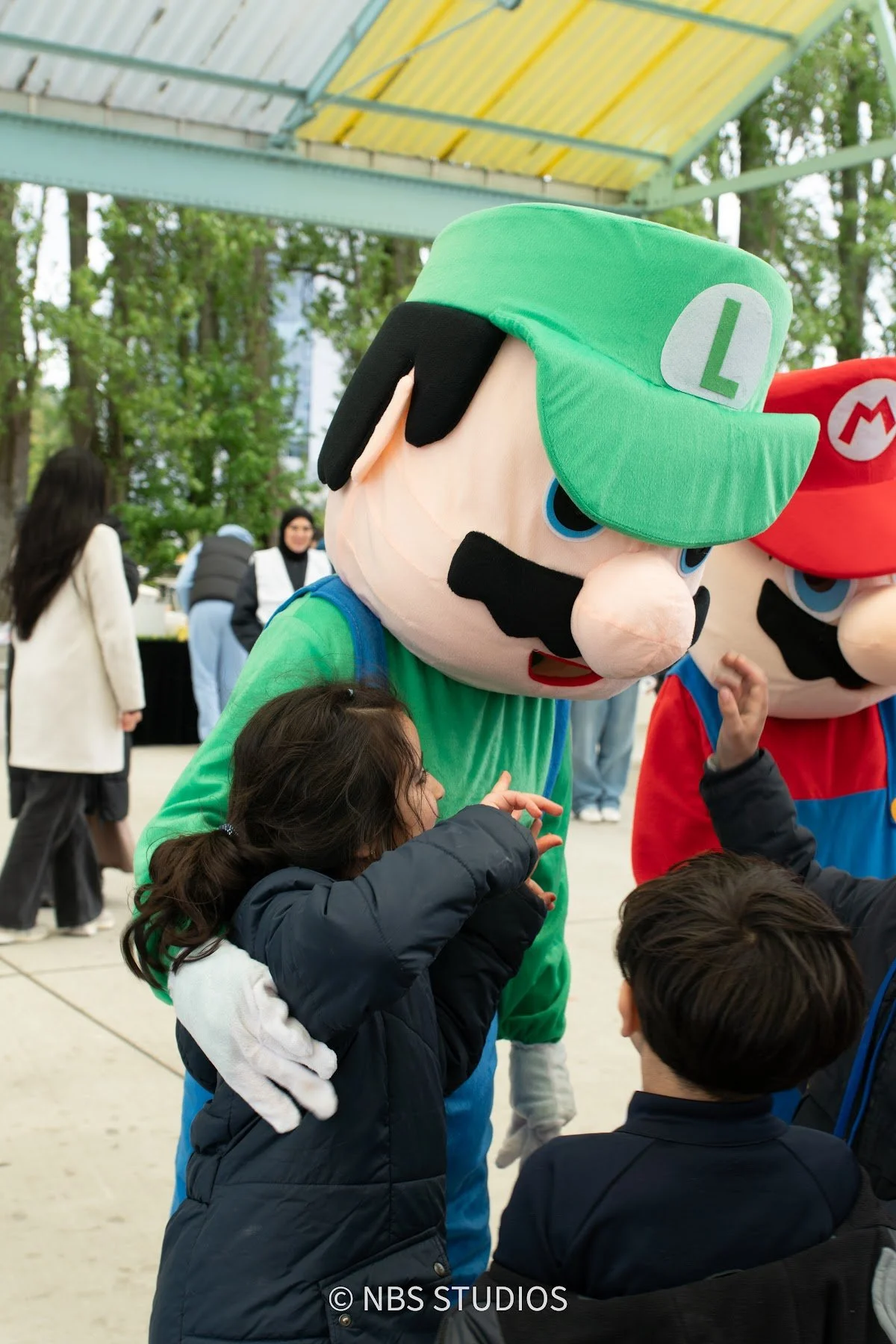 Luigi hugging a child at the Make A Kid Happy Eid Festival