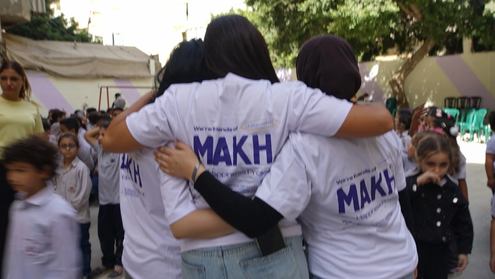 Make A Kid Happy volunteers hugging children during a school visit