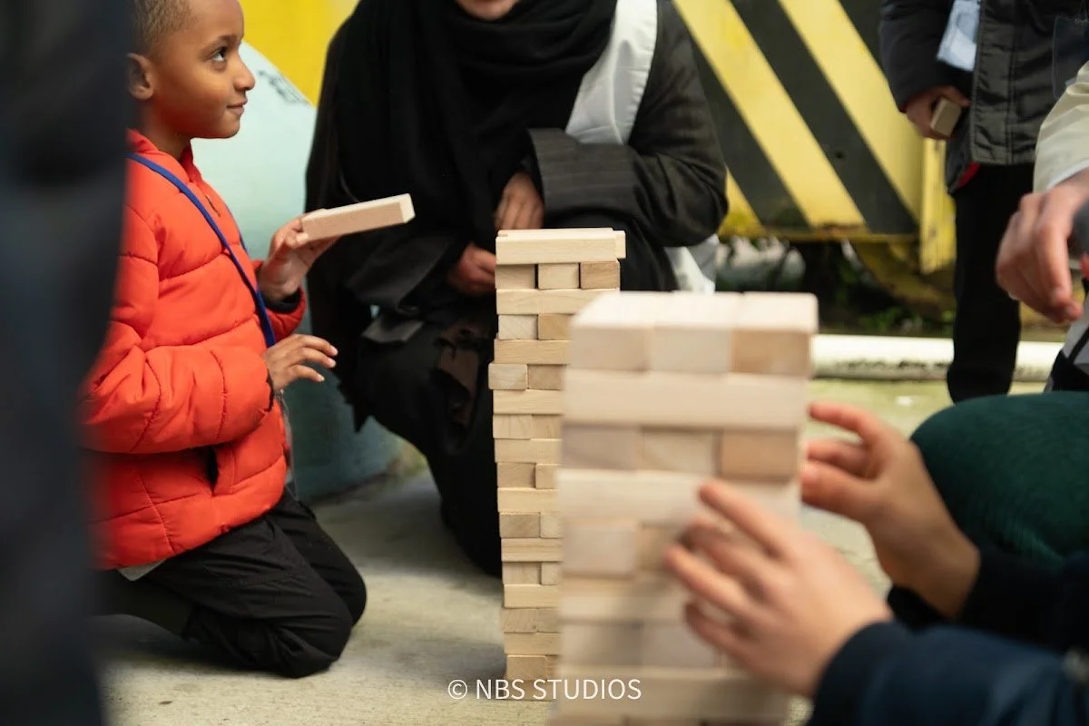 A boy carefully playing a giant game of Jenga