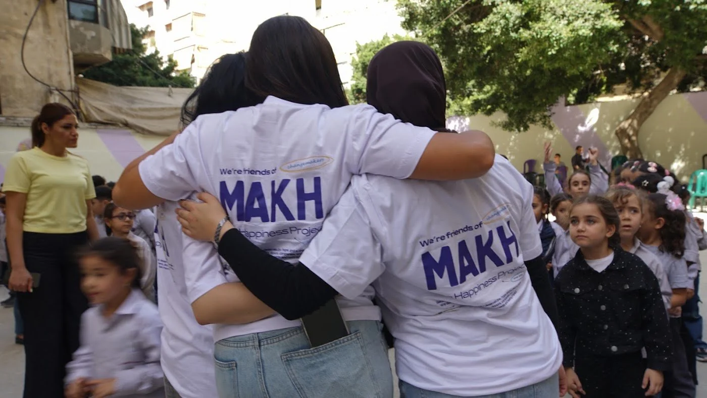 Make A Kid Happy volunteers hugging children during a school visit