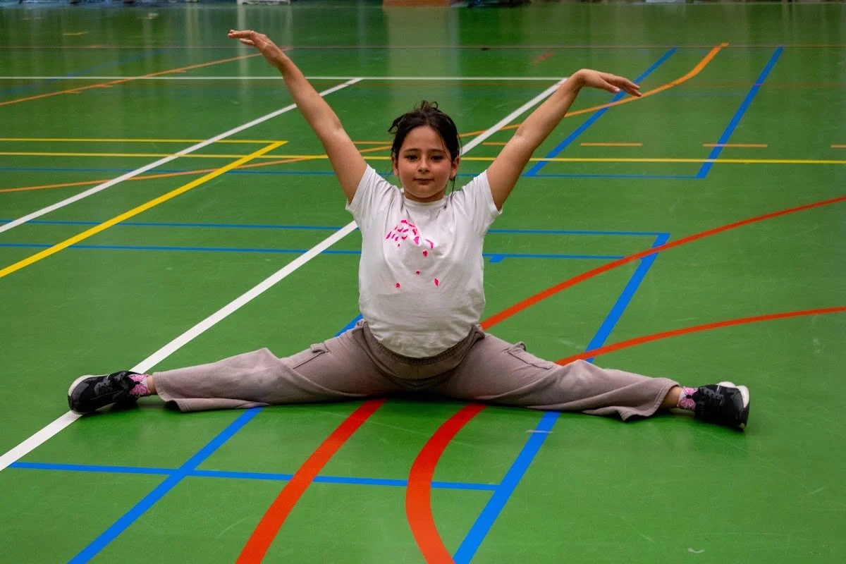 A girl doing the splits on the sports hall floor