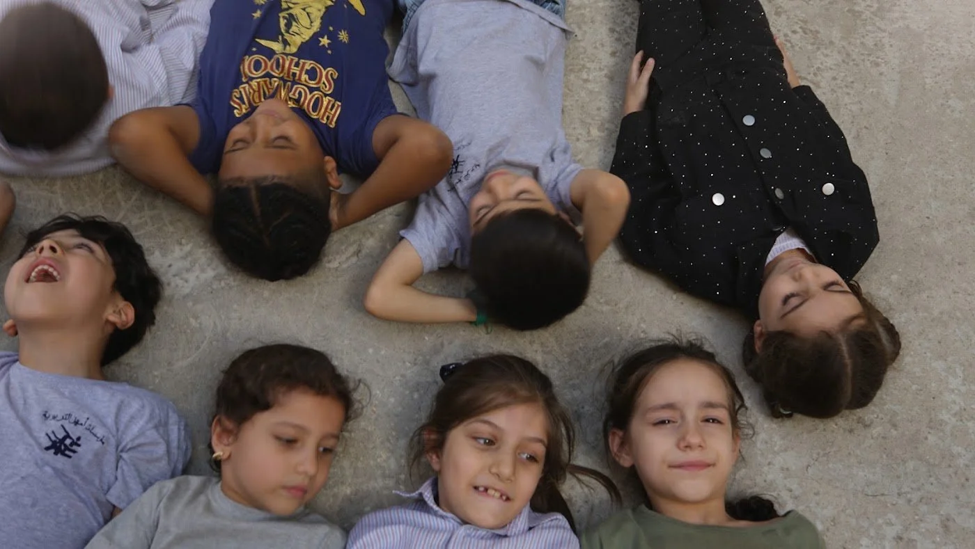 Children in school uniforms lying in a circle and smiling during a school activity