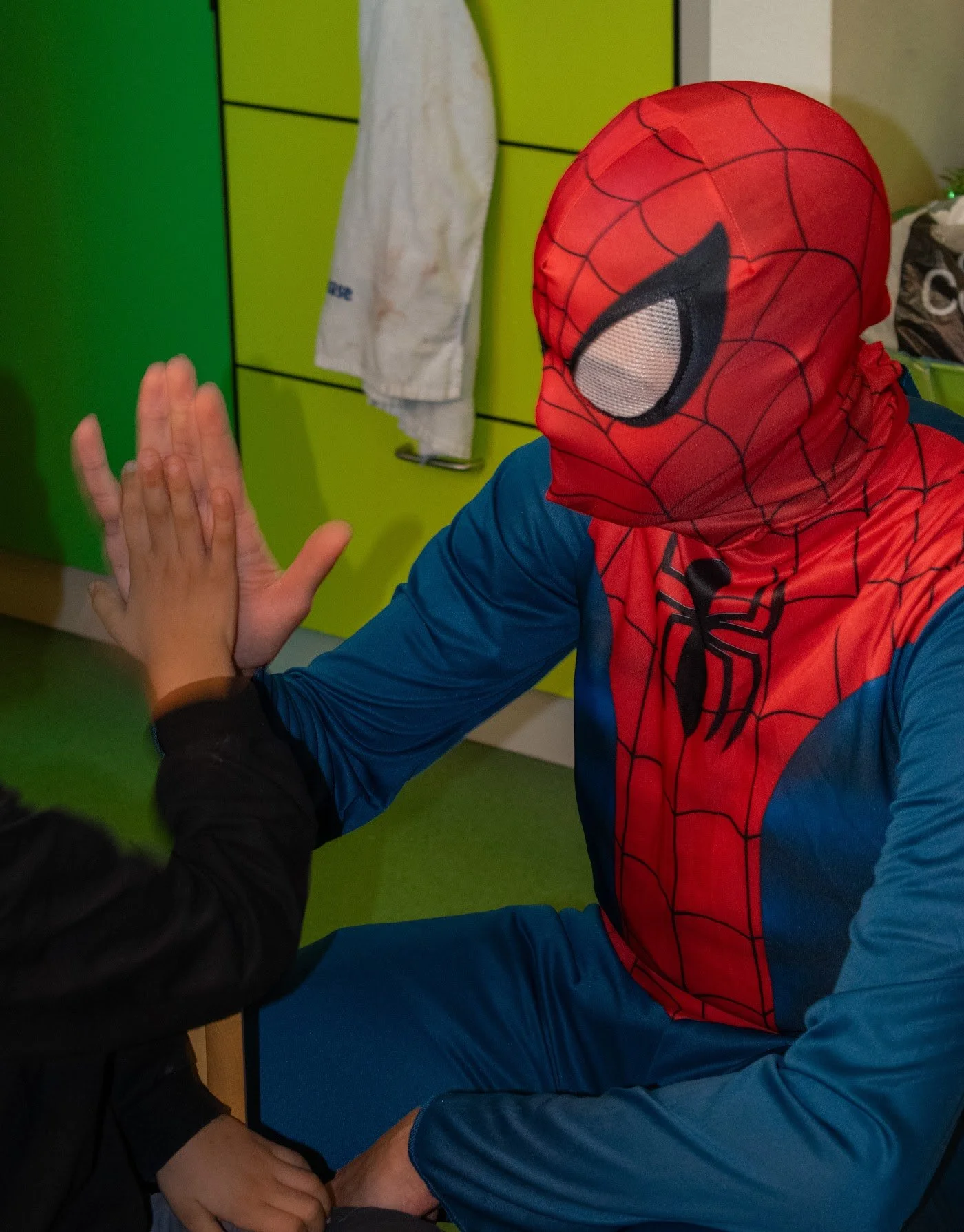 Spider-Man giving a child a high five during a Make A Kid Happy hospital visit