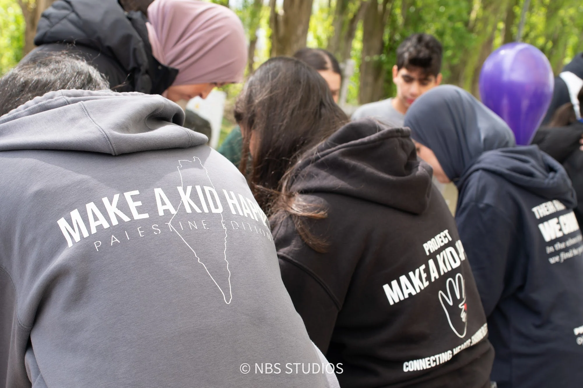 Volunteers in Make A Kid Happy hoodies among the children at the Eid Festival