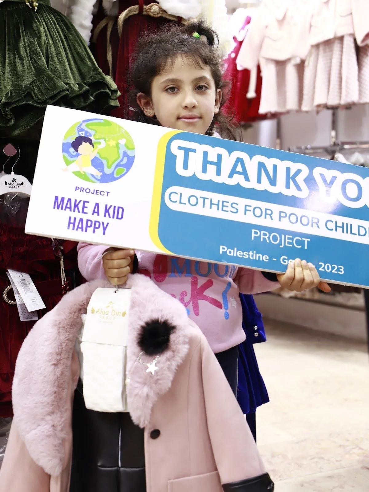 A girl holding a thank-you sign after receiving new clothes