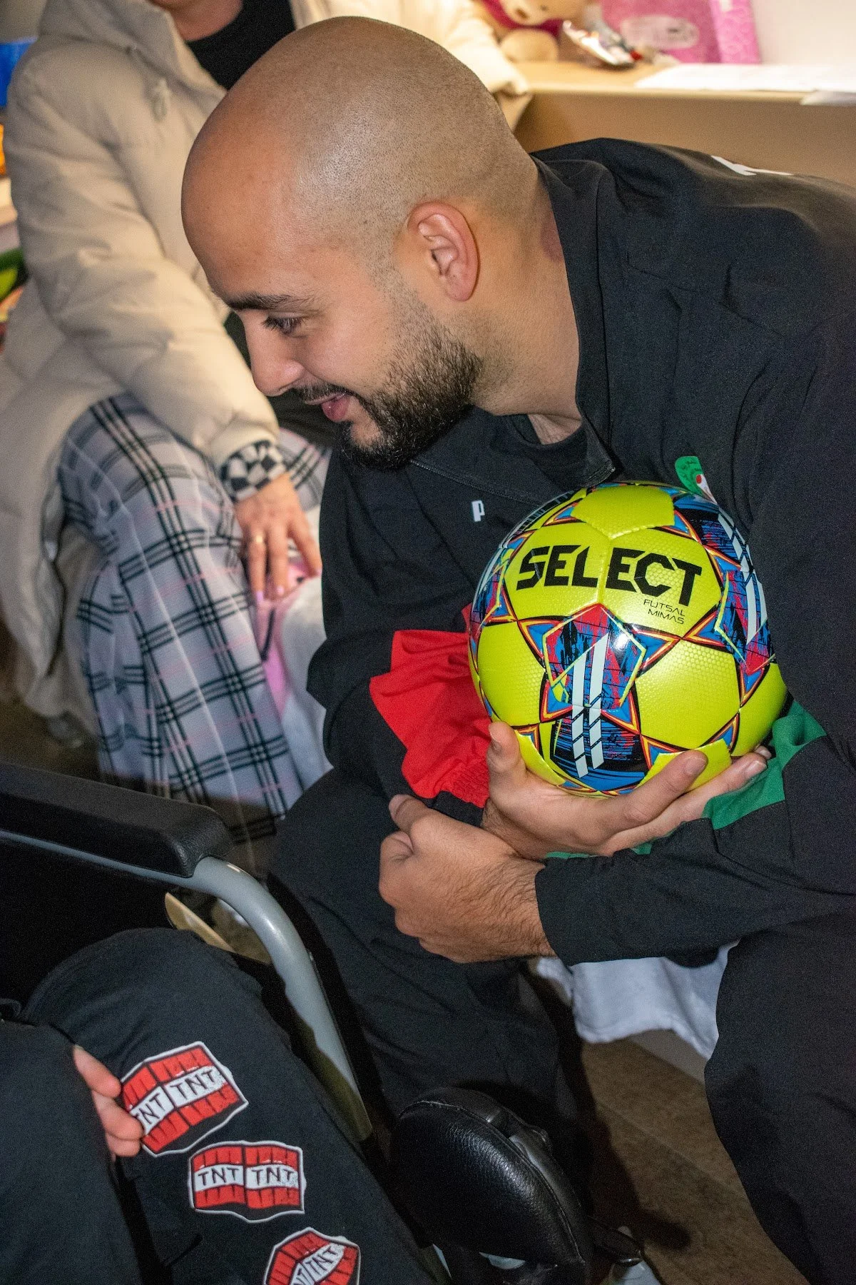 A visitor sharing a football with a child during a hospital visit