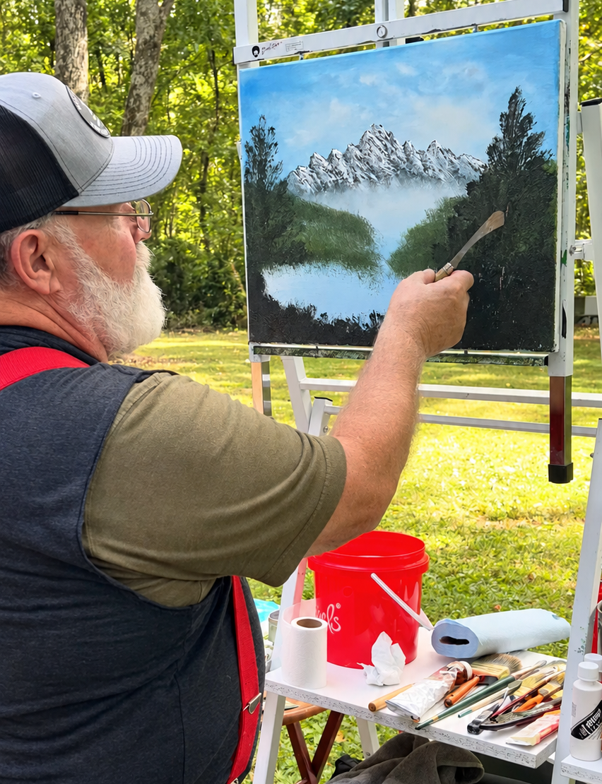 Johnny Harris painting a mountain landscape outdoors at his easel
