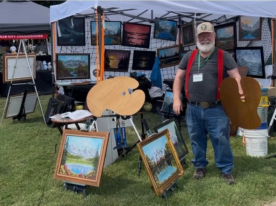 Johnny Harris at his art fair booth surrounded by original paintings