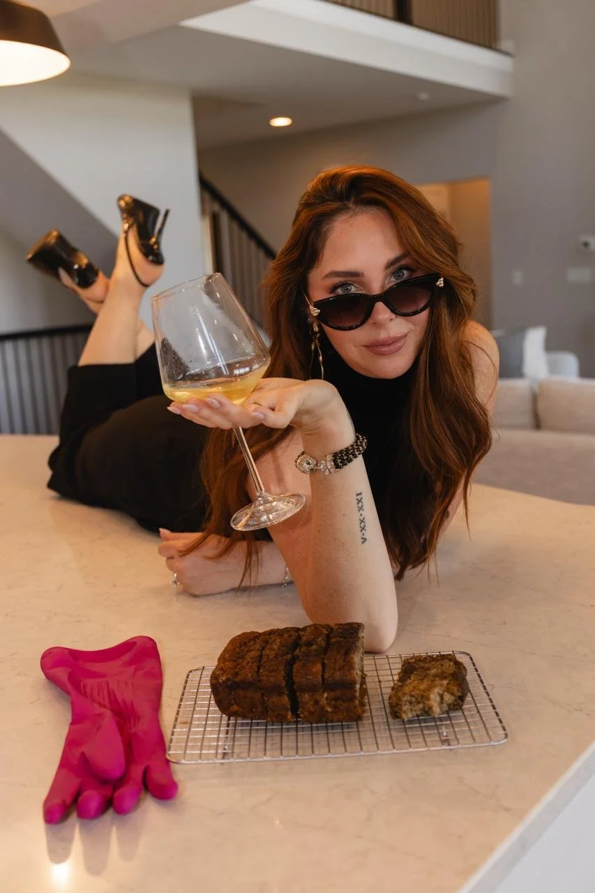 Katie lying on the kitchen counter with a glass of wine and banana bread