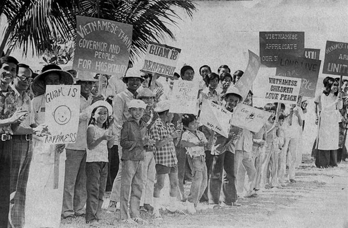 Vietnamese evacuees holding signs on Guam, 1975
