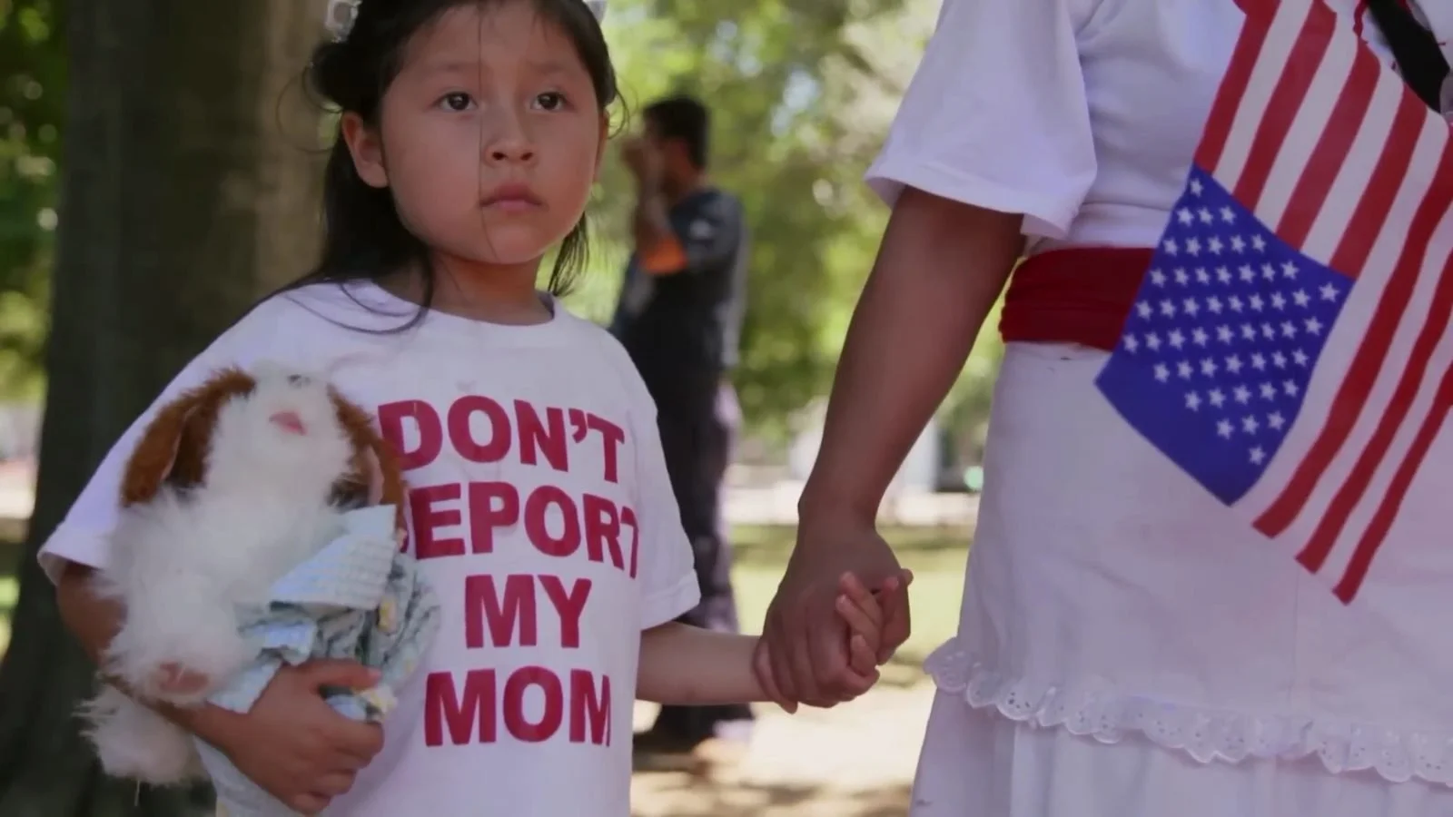 A girl holds a sign reading Don’t Deport My Mom at a rally