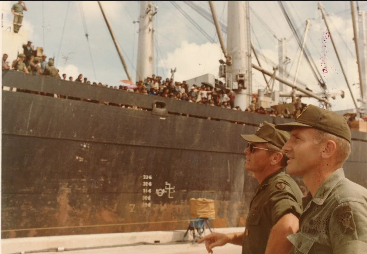 Soldiers on a pier beside a ship crowded with evacuees