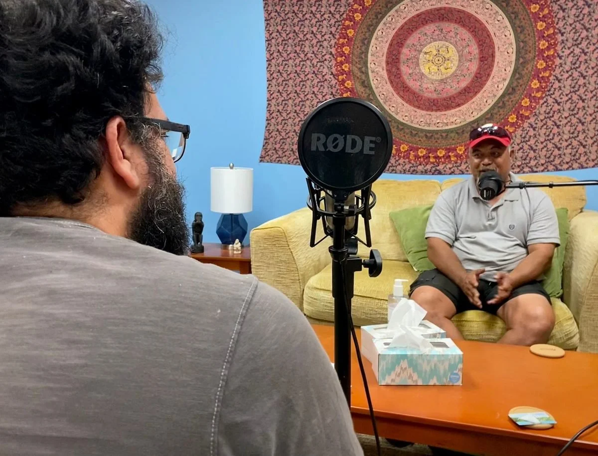An interviewer records a guest at a studio microphone