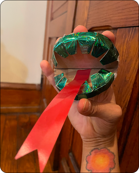 Hand holding a handmade green paper fortune teller with a red paper tongue