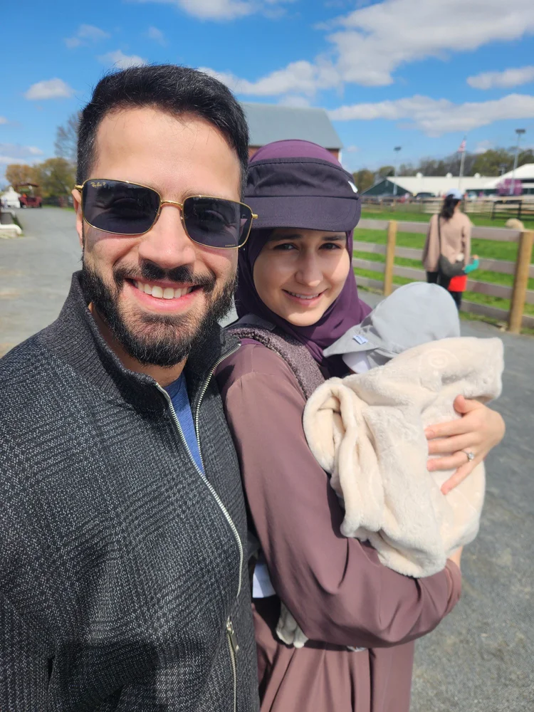 Nick's first grandson, bundled in a blanket, with family on a farm outing