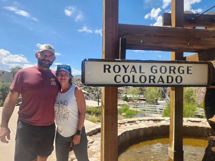 A couple standing beside the Royal Gorge, Colorado sign