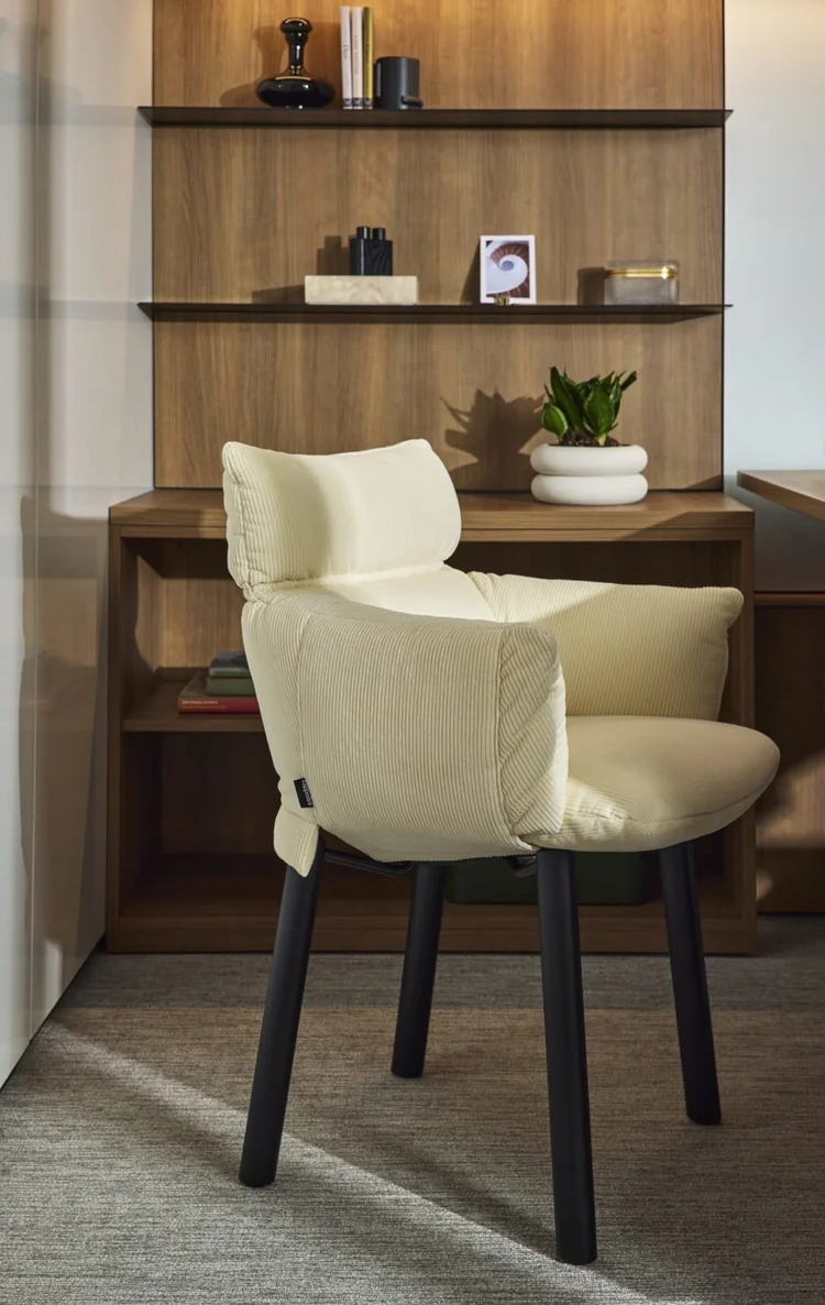 Cream corduroy lounge chair by wood shelving