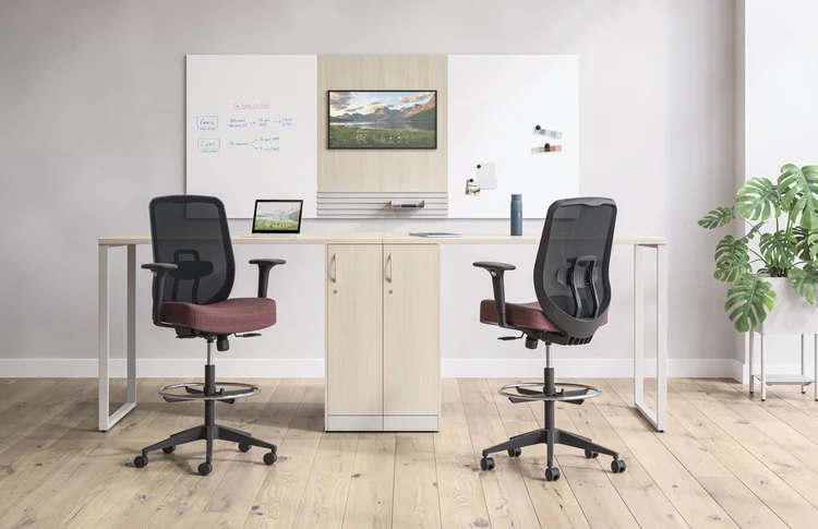 Black mesh task stools at a standing-height desk