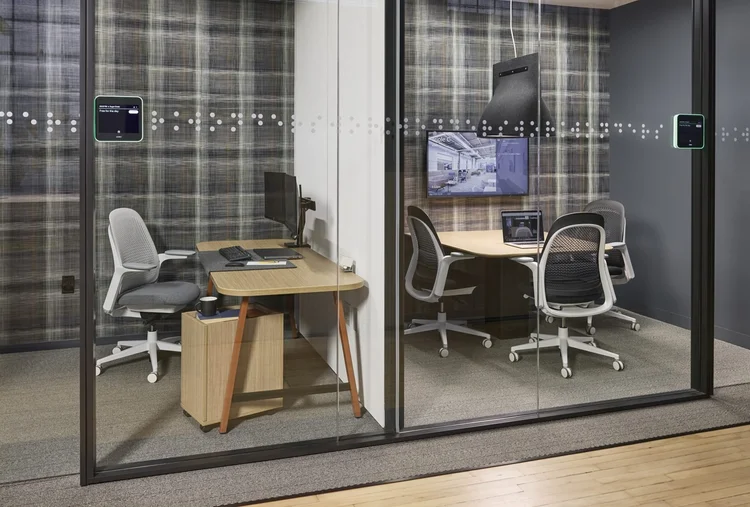 Glass-walled offices with a desk and small meeting table