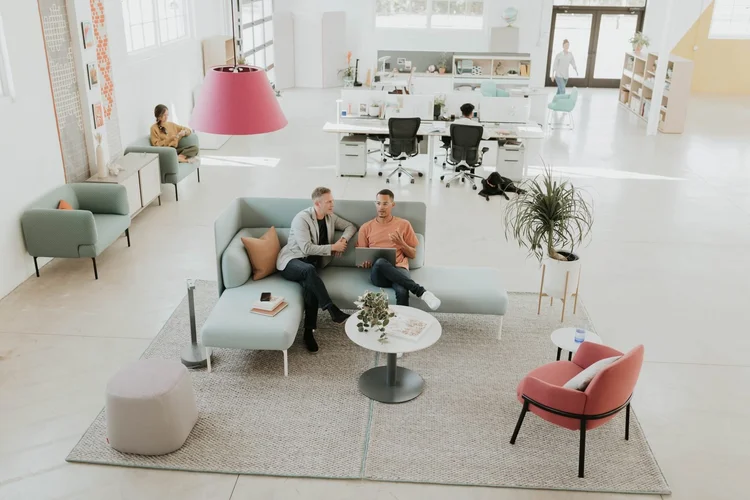 Two colleagues talking on a mint sofa in an open studio
