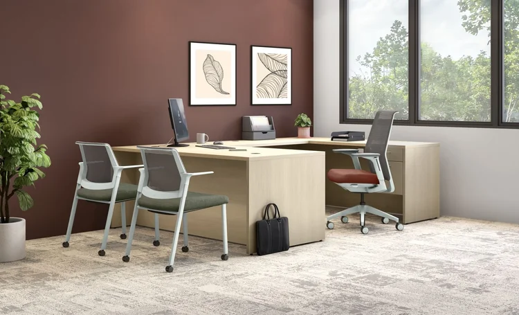 L-shaped desk with guest chairs against a burgundy wall