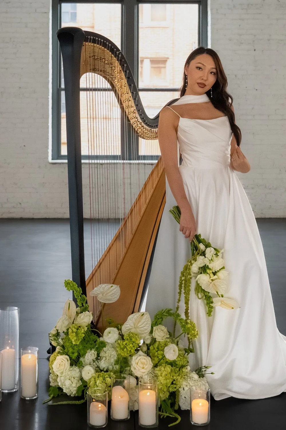 Bride standing beside a harp and candles