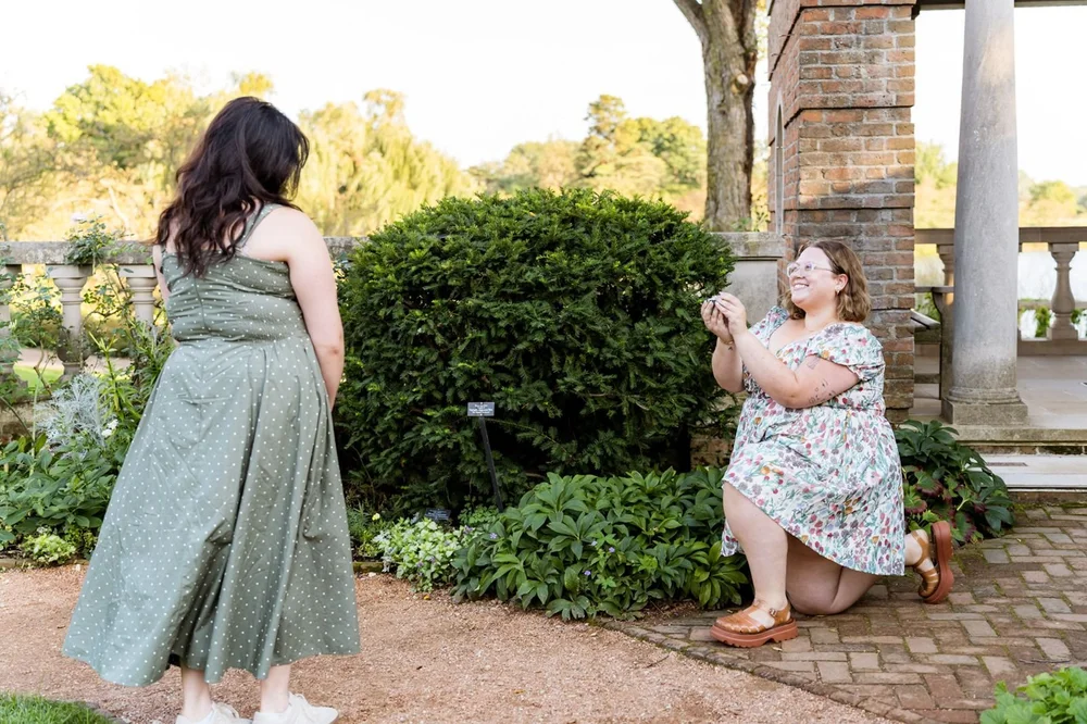A proposal on one knee in a formal garden with stone columns