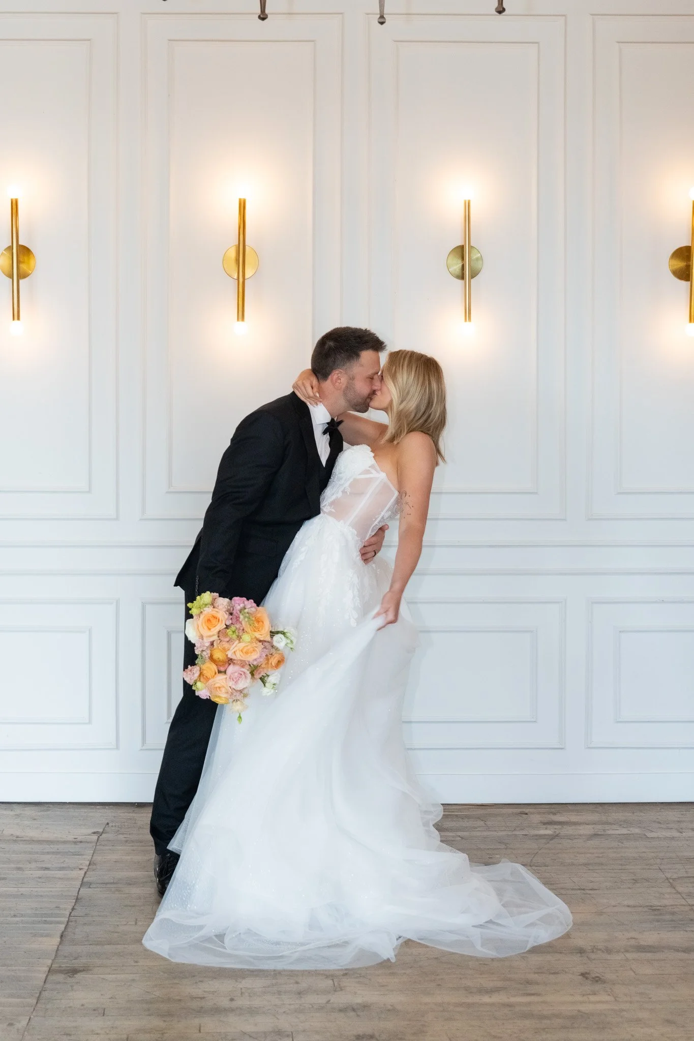 Couple kissing beside gold sconces