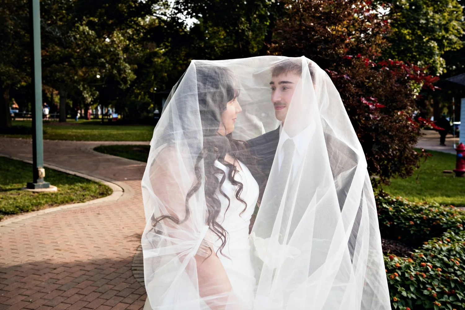Couple sharing a moment under a long veil in the park