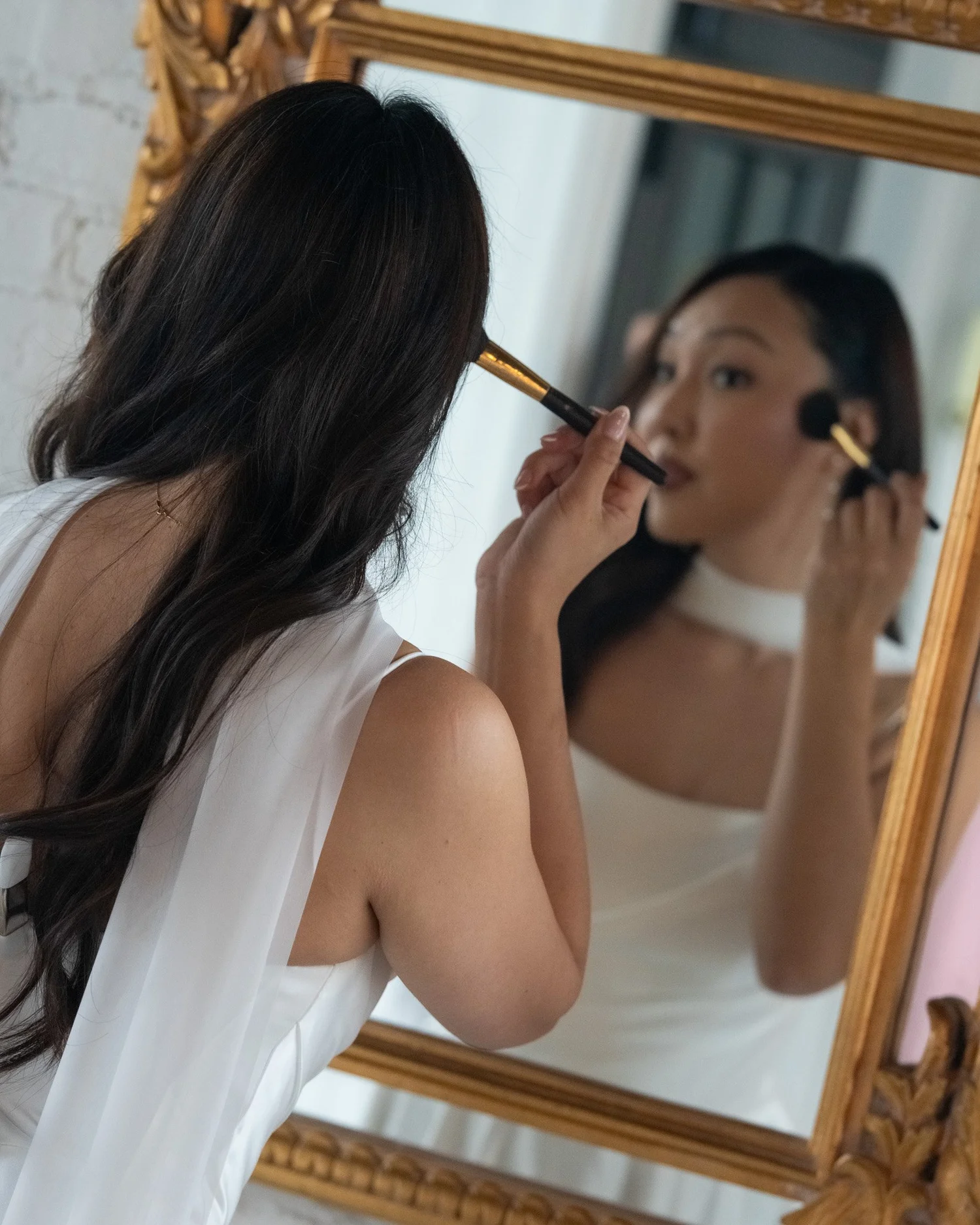 Bride doing makeup in a gold mirror