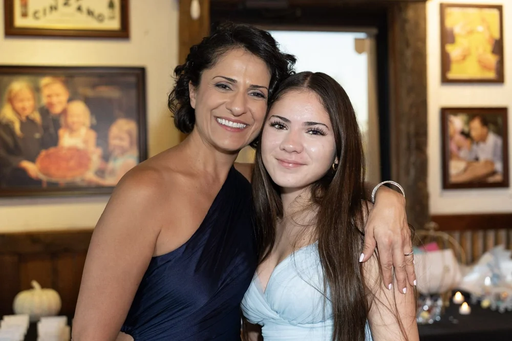 Mother and teenage daughter cheek to cheek at a celebration
