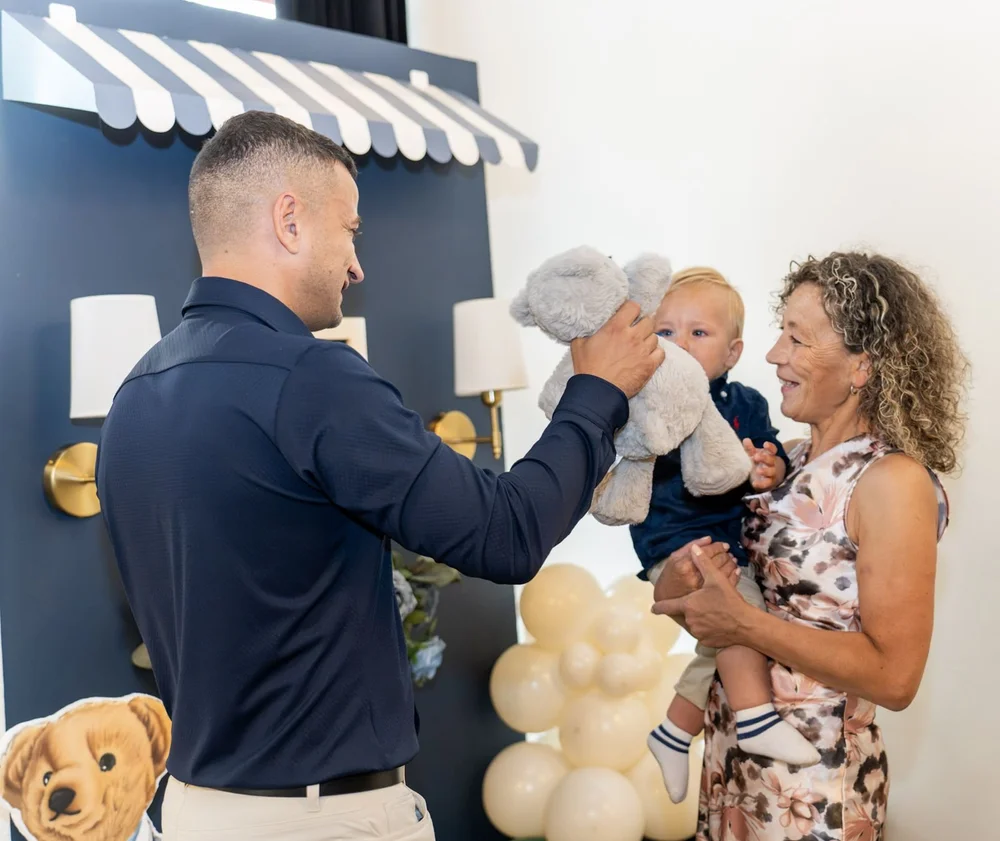 Father lifting a teddy bear to make his baby laugh at a first birthday