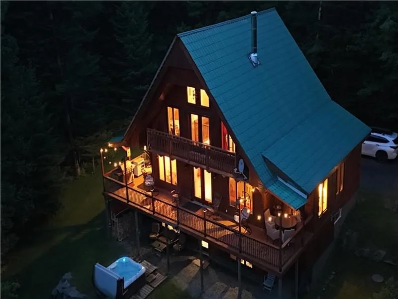 Vue aérienne du chalet illuminé la nuit, au milieu de la forêt