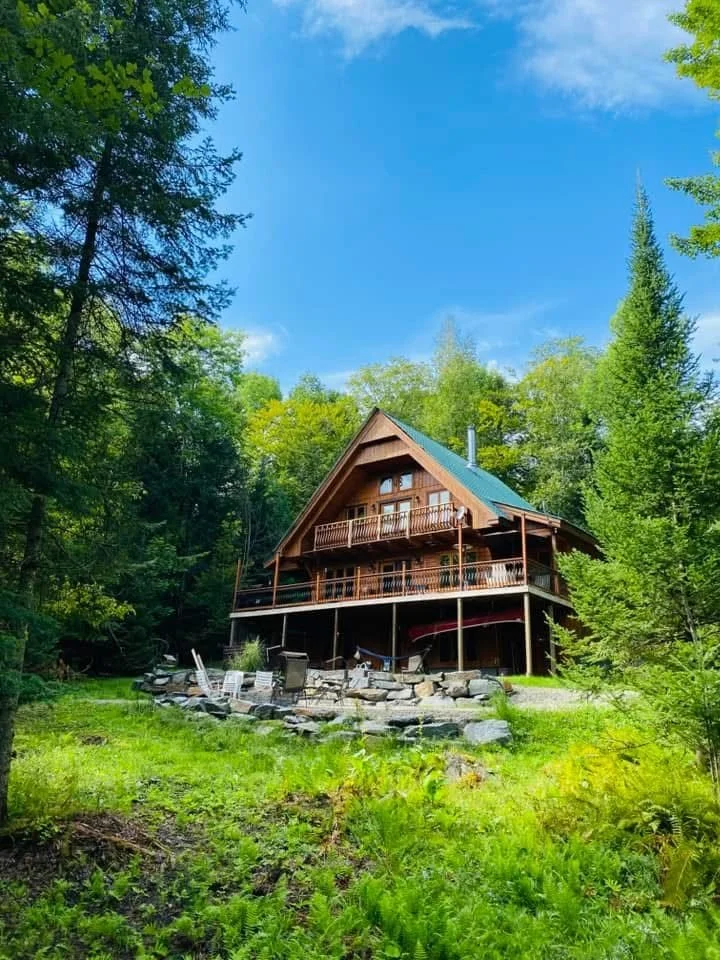 Le chalet Hopelaï en été, entouré de grands conifères