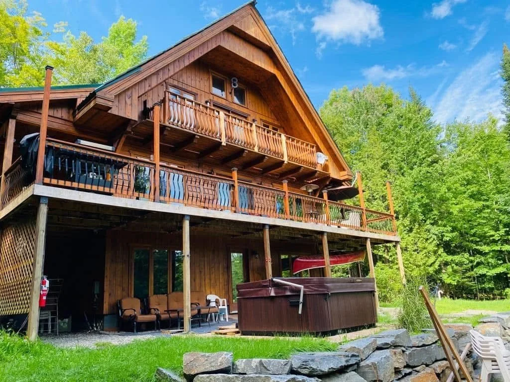 Le chalet en été, avec sa grande galerie et son spa